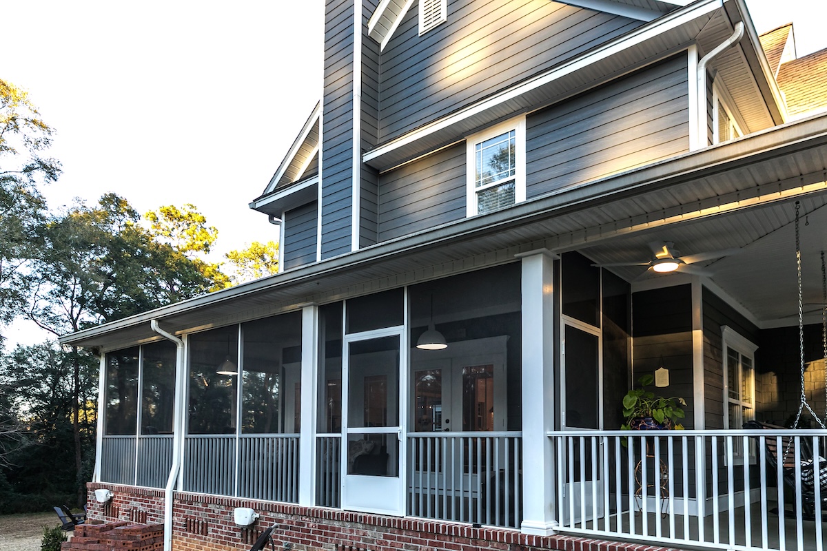 Side view of a large two story blue gray house with wood and vinyl siding