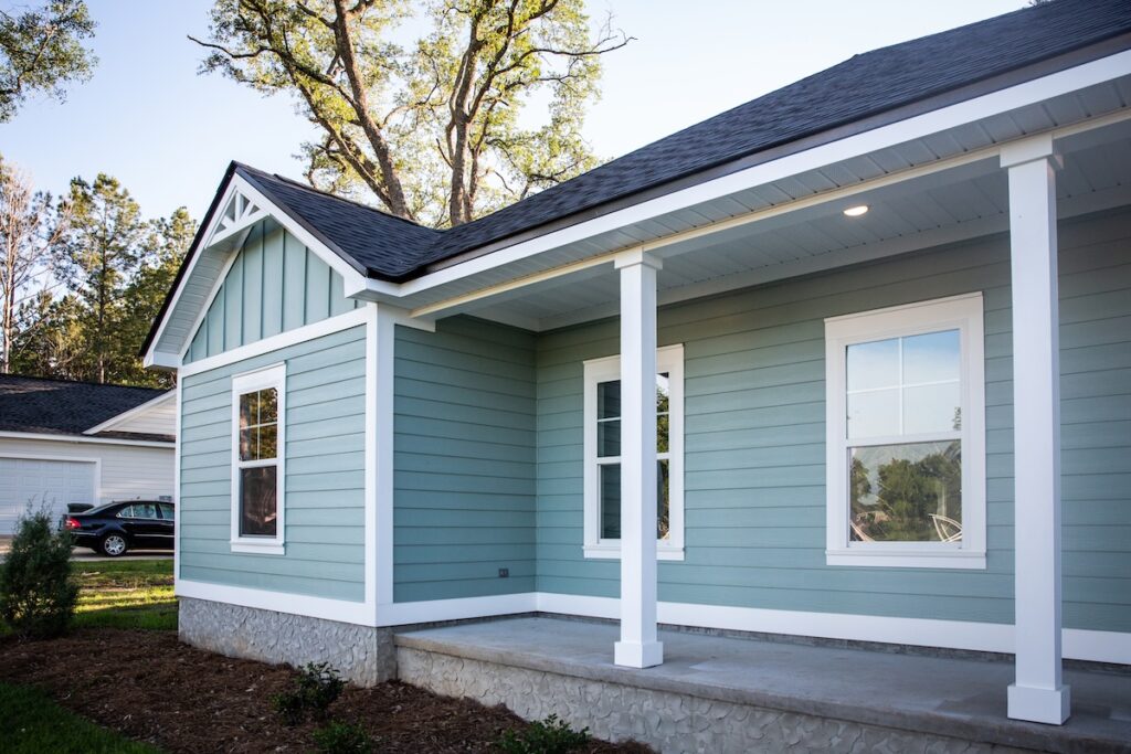 Front view of a brand new construction house with blue siding, a ranch style home with a yard