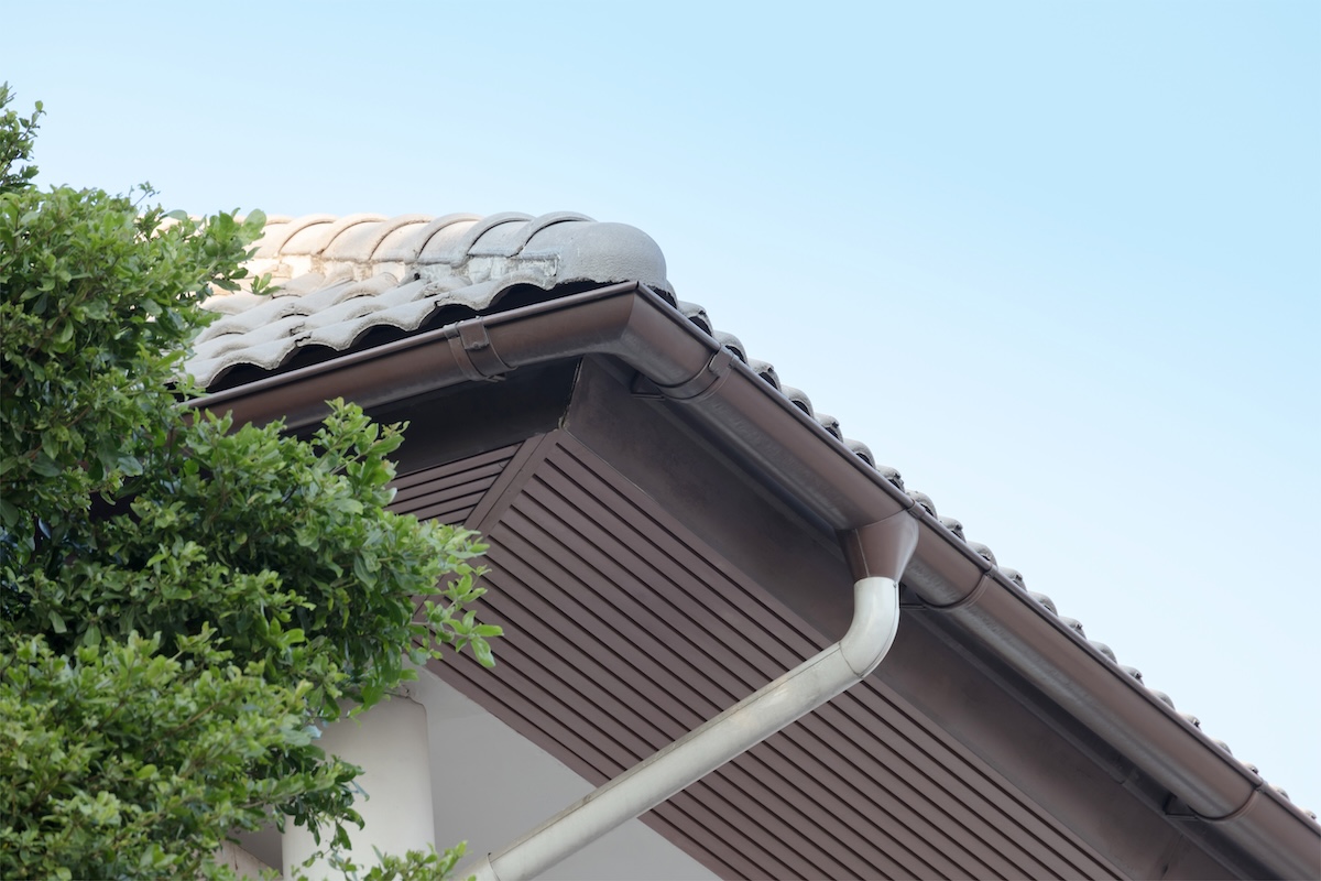 rain gutter on top of roof against blue sky on background