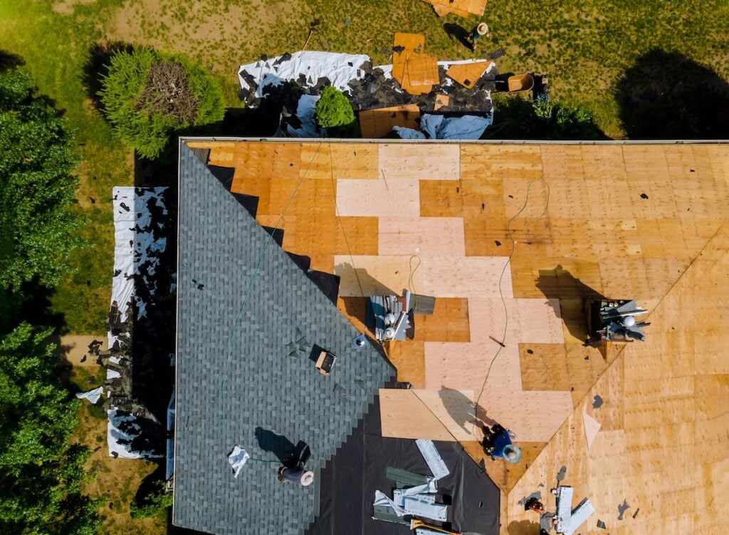 Home with roof replacing new shingles, felt paper, and tools a worker replaces shingles