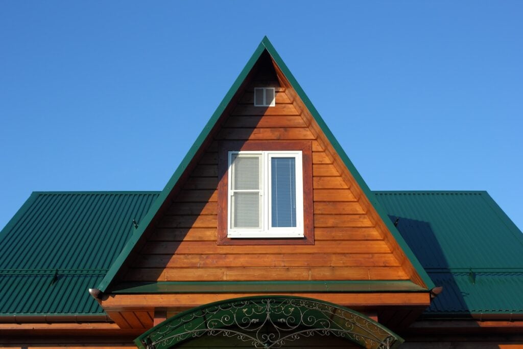 Green metal roof  and attic window closeup photo
