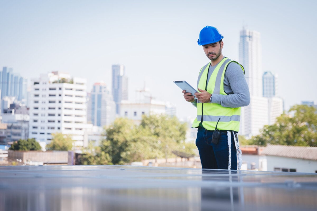 Smart engineer maintenance in solar power plant checking installing photovoltaic solar modules with digital tablet and using walkie talkie. Concept of sustainable resources, saving energy.