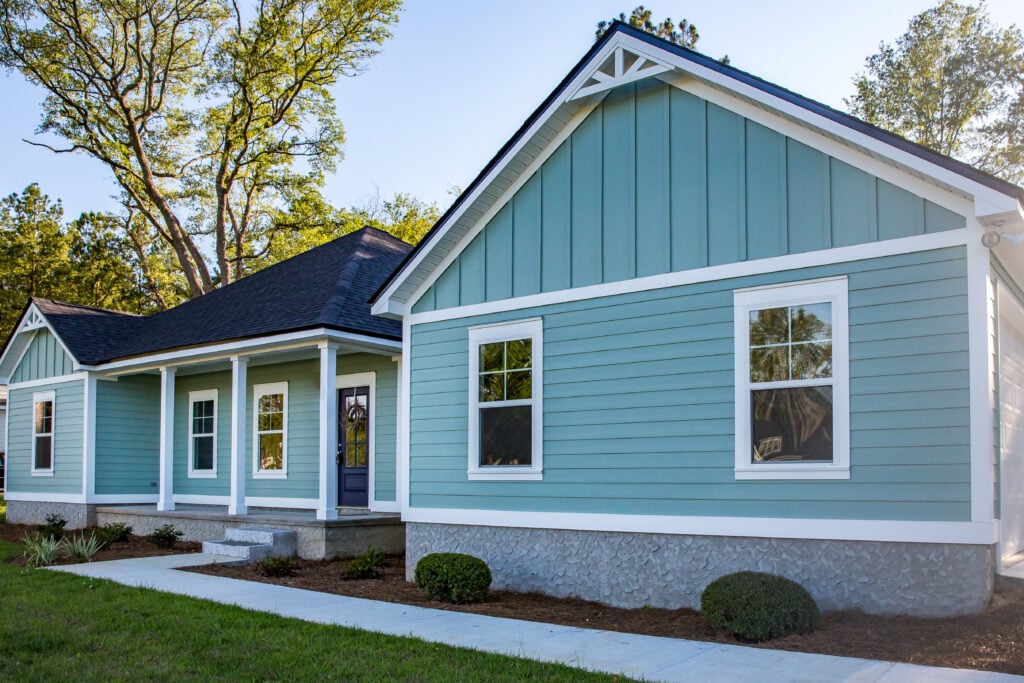 Front view of a brand new construction house with blue siding, a ranch style home with a yard