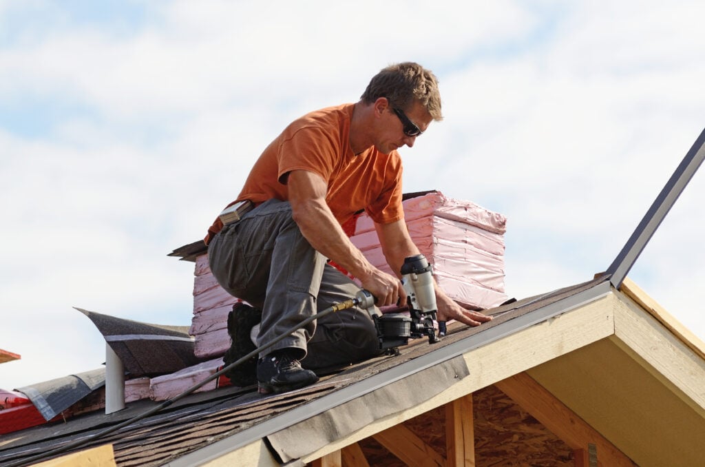 Building contractor putting the asphalt roofing on a large commercial apartment building development