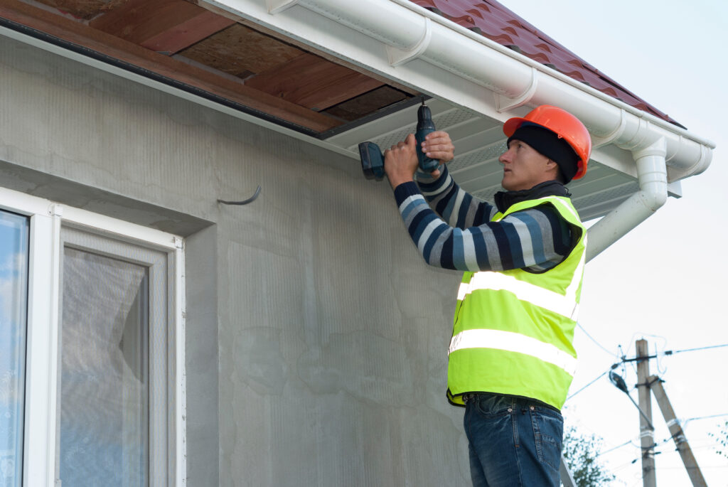 soffit and fascia repair construction worker mounts a soffit on the roof eaves