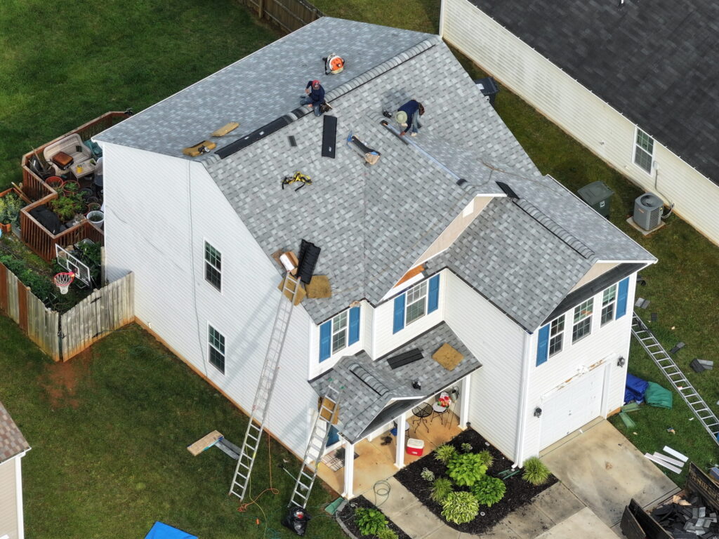 roofing companies garner nc roofers repairing grey roof white big house drone shoot