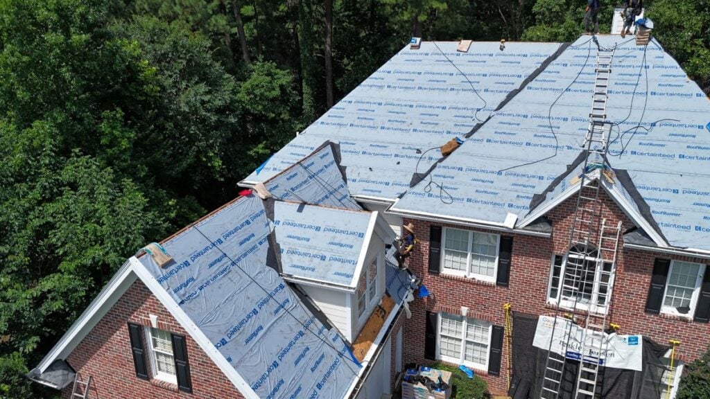 roofing companies garner nc branded Barkley-Jensen worker repairing roof blue cover stairs