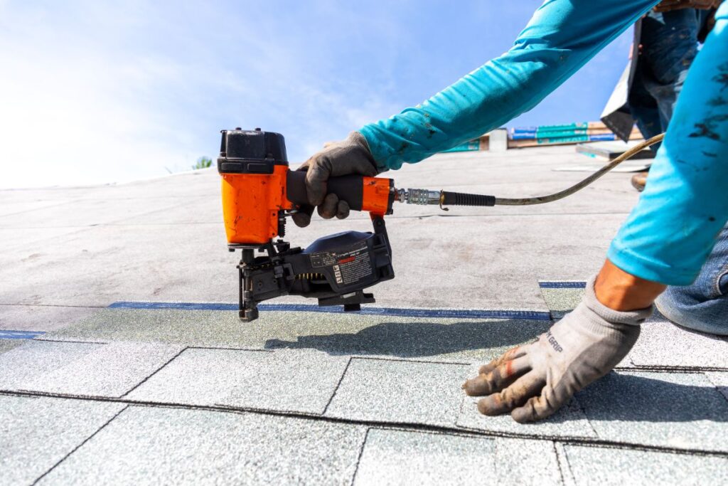 roofing companies garner nc worker installing roof shingles with nail gun