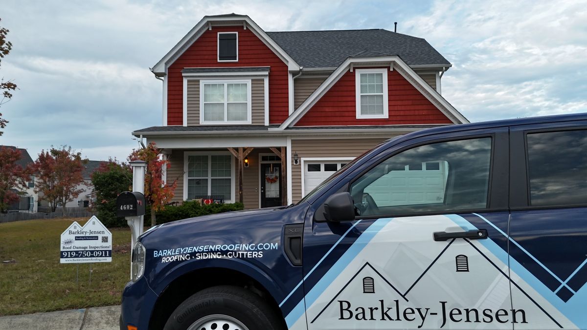 roofing companies raleigh nc branded truck outside of red house with shingles roof Barkley-Jensen Roofing