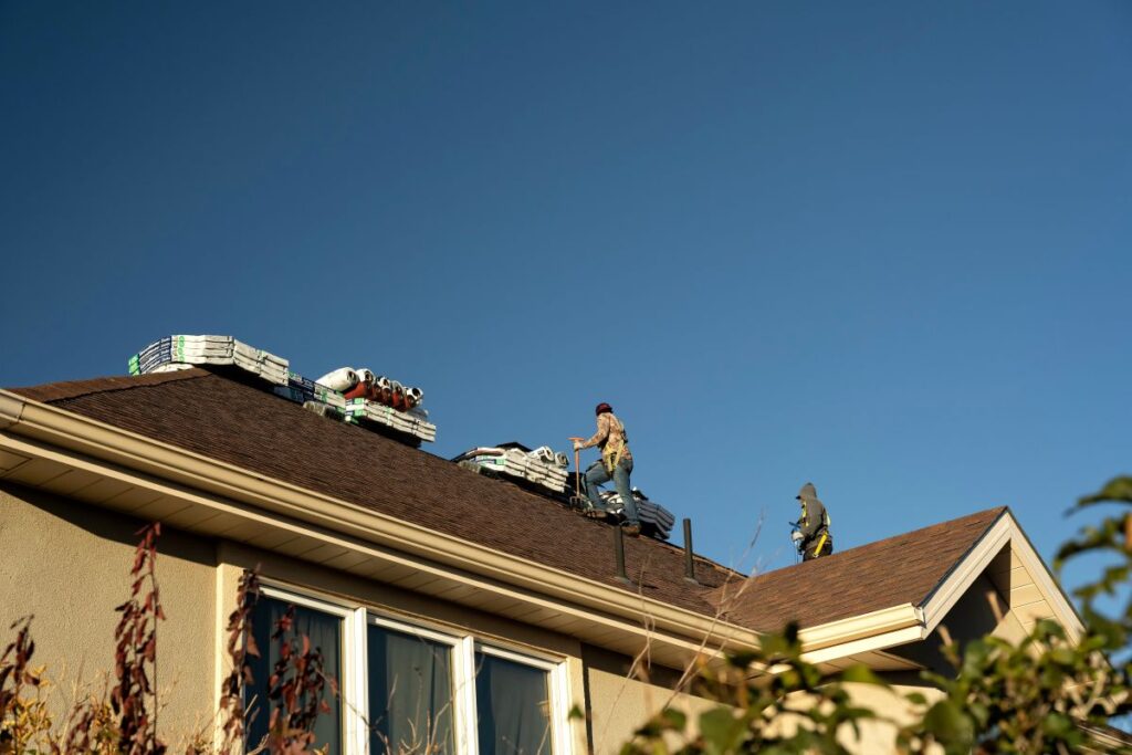 Roof hail damage workers repairing brown shingles after storm