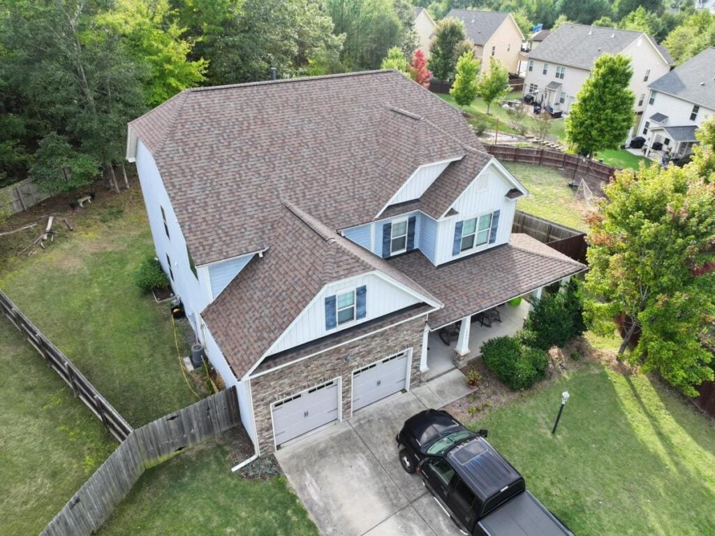 A tan shingle roof on a large, white house