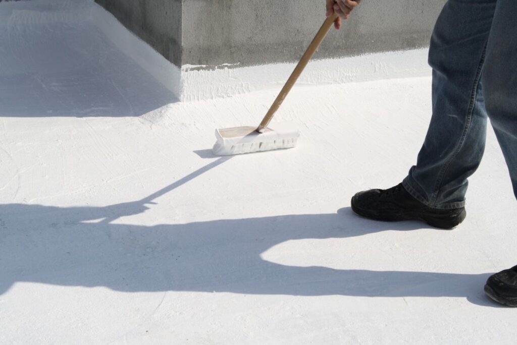commerical roof coating worker applying white silicone coat