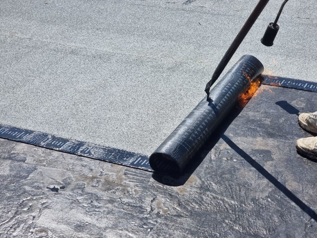 commerical roof coating worker installing asphalt coat